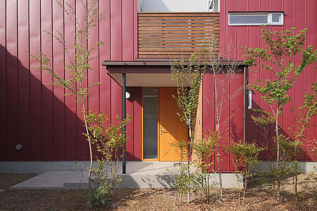 赤いガルバリウム鋼板と木板張りのナチュラルモダンな住宅の外観,玄関ポーチ