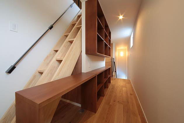 2階廊下・小屋裏収納への可動木製梯子,廊下の脇に造り付けた棚により多目的な使用ができる廊下になっている